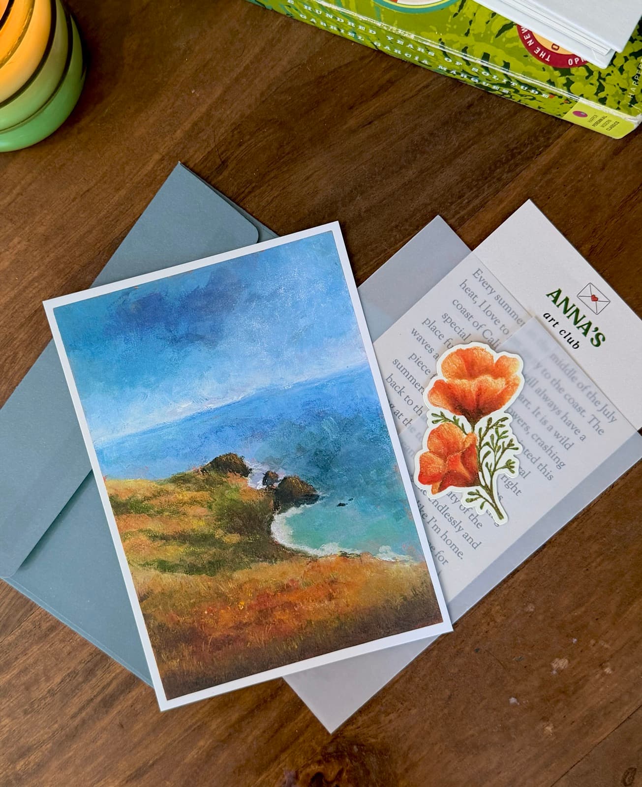 Anna's Art Club note card, coastal print, and poppy sticker tucked into a soft blue envelope.